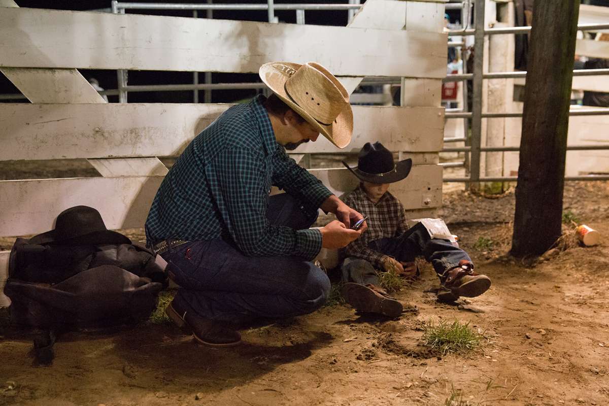 John Headley, 10, with his father, keeps an ice pack on his leg after the junior bull riding competition. (Lindsay Lazarski/WHYY) 