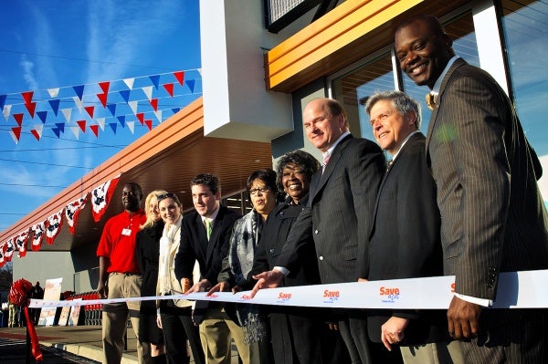 Save-A-Lot operator Shawn Rinnier ceremonially cut a ribbon to mark the opening of Germantown's newest supermarket Friday morning. City Councilwoman Donna Reed Miller and Chelten Plaza developer Patrick Burns -- fourth and third from the right -- were among those flanking Rinnier. (Bas Slabbers/for NewsWorks)