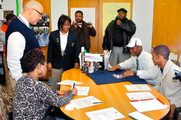 Will Parks's mother Nyerere signs paperwork that his father would immediately fax to the University of Arizona. (Bastiaan Slabbers/for NewsWorks)