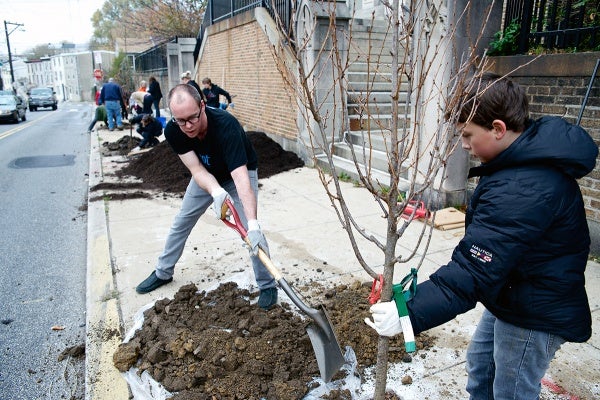 <p><p>"It is a good day for planting trees," said J.D. Cramer. He and 10-year-old Landen Banks are working on one of the five trees. (Bas Slabbers/for NewsWorks)</p></p>
