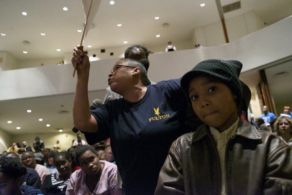 <p>Fulton fifth grader Quidier Mitchell stands by as his grandmother takes the microphone. (Bas Slabbers/for NewsWorks)</p>

