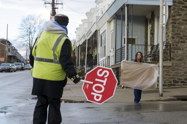<p><p>Chris Bartholomew blocks traffic for a young girl to cross the street with a school project. (Bas Slabbers/for NewsWorks)</p></p>
