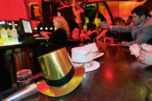 <p>New Years Eve themed hats lay on the bar of the Ivan Kane's Royal Jelly Burlesque Nightclub and in the background a performer dances for the patrons. (Bas Slabbers/for NewsWorks, file)</p>
