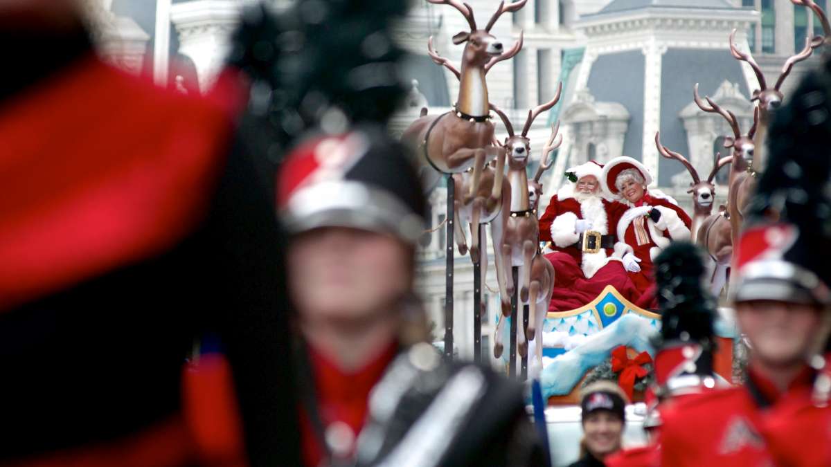 Mr. and Mrs. Santa are seen clearly enjoying the attention they get as they ride up the Parkway in a sled pulled by Dasher, Dancer, Prancer, Vixen, Comet, Cupid, Donner, and Blitzen. (Bas Slabbers/for NewsWorks)