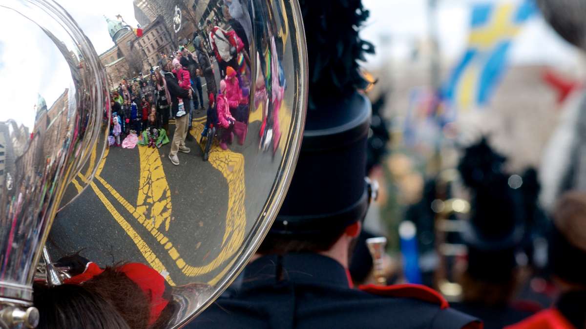Crowds that line the parade route are seen reflected in one of the instruments of a marching band. (Bas Slabbers/for NewsWorks)