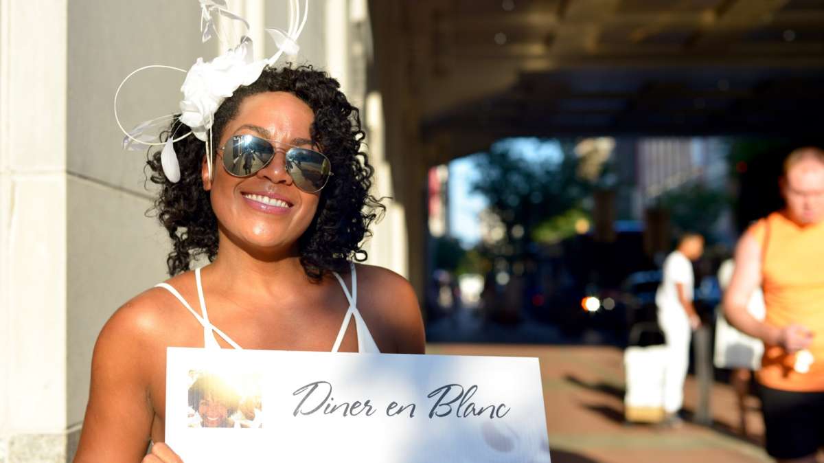 At one of the pickup locations, a hostess waits for a group participating in this year's Dîner en Blanc.