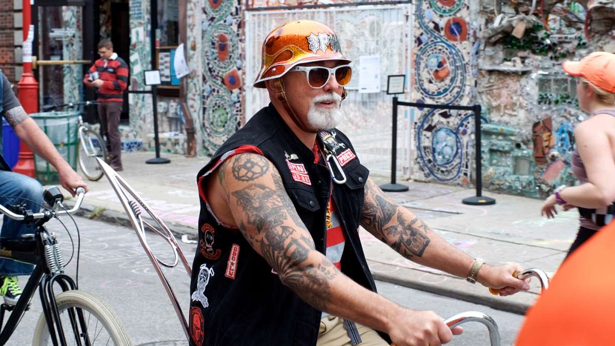 Mike ''Spin'' Spinelli, president of the Jersey Devils Bicycle Club, passes Isaiah Zagar’s Magic Gardens as he rides with others on vintage and custom cruisers over South Street during the Philly Free Streets day.