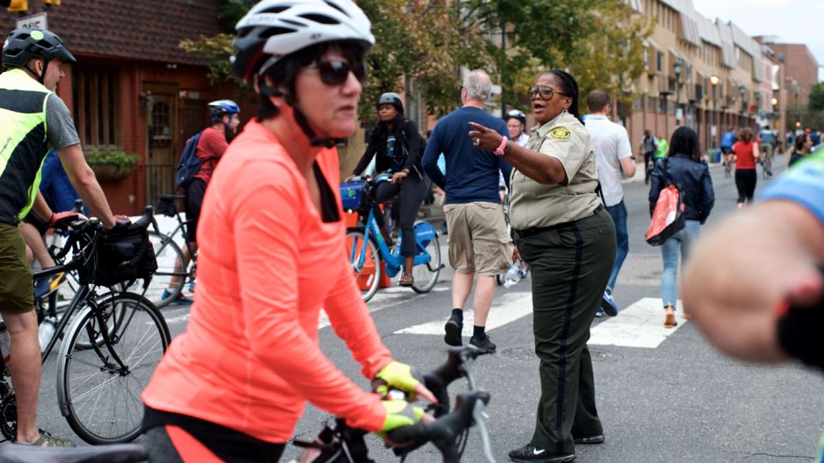 Javese Phelps-Washington, a Sanitation Enforcement Officer with the City, yells encouraging words to all the cyclists and runners at 21st and South streets.