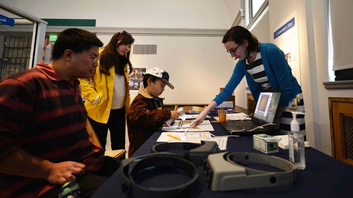 Julia Commander, an intern at the Artifact Lab of Penn Museum, shows JiaJing Zhang how papyrus looks through a microscope.