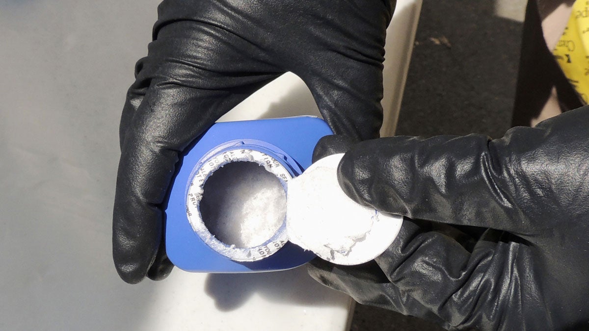  In this June 27, 2016 photo provided by the Royal Canadian Mounted Police, a member of the RCMP opens a printer ink bottle containing the opioid carfentanil imported from China, in Vancouver. (Royal Canadian Mounted Police via AP) 
