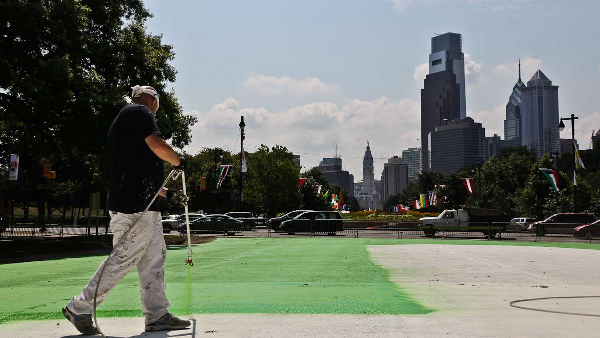 Howard Stokes spray paints the Eakins Oval parking lot Friday. He calls the neon colors 'wild.' (Kimberly Paynter/WHYY)