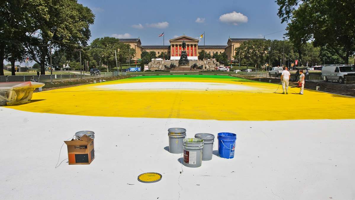 Painters begin to turn Eakins Oval on the Parkway into a magic carept Friday morning. (Kimberly Paynter/WHYY)