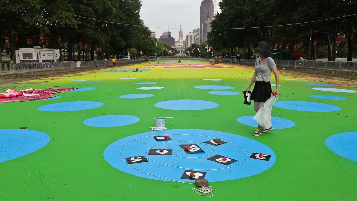 Artist Candy Coated lays out a hopscotch game on the Eakins Oval magic carpet. (Kimberly Paynter/WHYY)