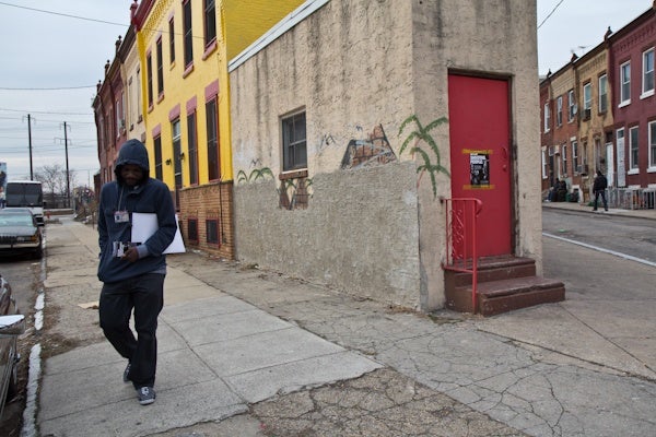 Outreach workers for CeaseFire Philadelphia hand out pamphlets and hang up fliers. (Kimberly Paynter/For NewsWorks)