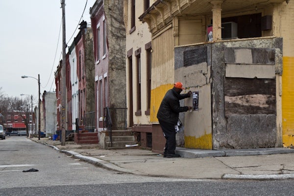 CeaseFire Philadelphia volunteer Anton McCullough posts fliers onto abandon buildings in North Philadelphia. (Kimberly Paynter/For NewsWorks)