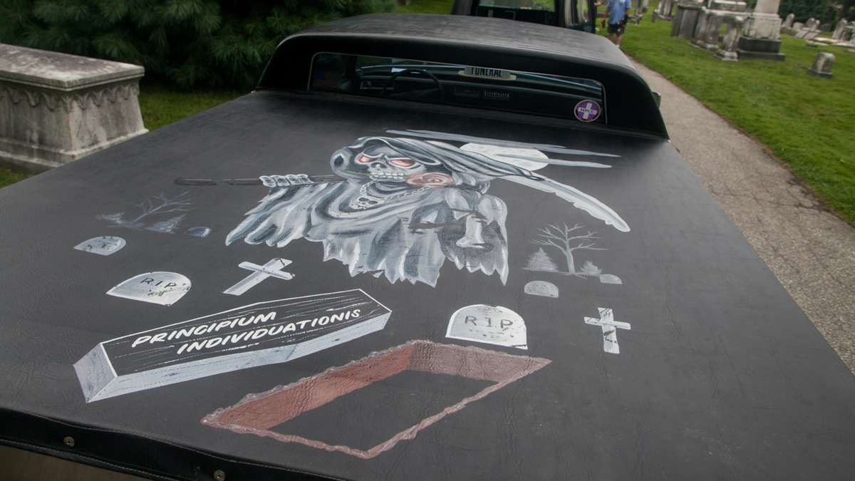 A grim reaper painting is seen on the cover of a modified Cadillac hearse with the rear section of the roof removed and converted into a truck bed. (Brad Larrison for NewsWorks)