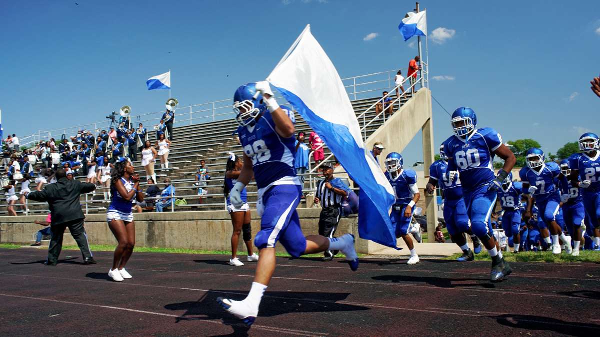 Senior Christian Sanchez caries the flag as the Cheyney University Wolves enter O'Shields-Stevenson Stadium for the 'Battle of the Firsts' against Lincoln University Lions. Cheyney is the country's oldest institution of higher learning for black students, while Lincoln was the first one to grant degrees. (Bastiaan Slabbers/for NewsWorks)