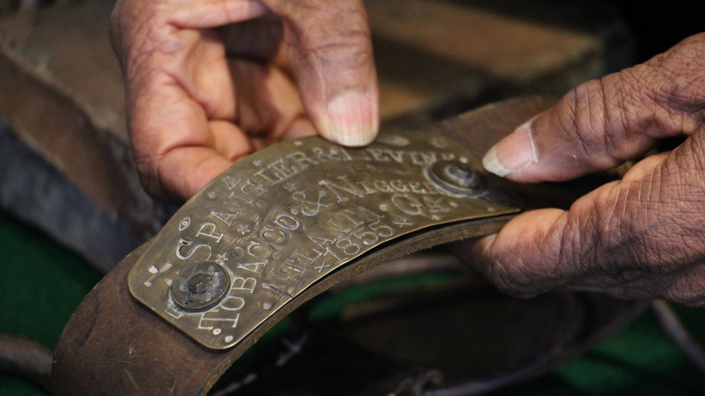 Louise Calloway holds a slave collar embelished with the name of an Atlanta, Georgia company that traded in tobacco and slaves. (Emma Lee/WHYY)