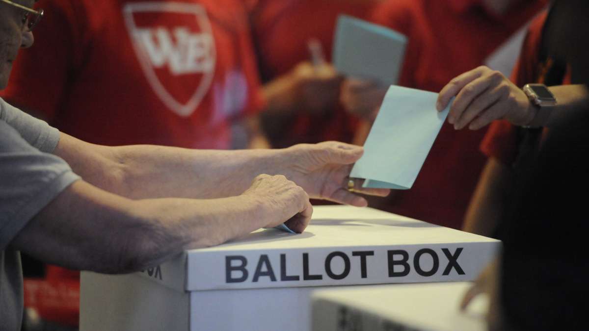 A member of the Philadelphia teachers union hands in a ballot Monday night at Temple University's Liacouras Center as the Philadelphia Federation of Teachers voted on a contract proposal. The plan that runs through 2020 won overwhelmingly.