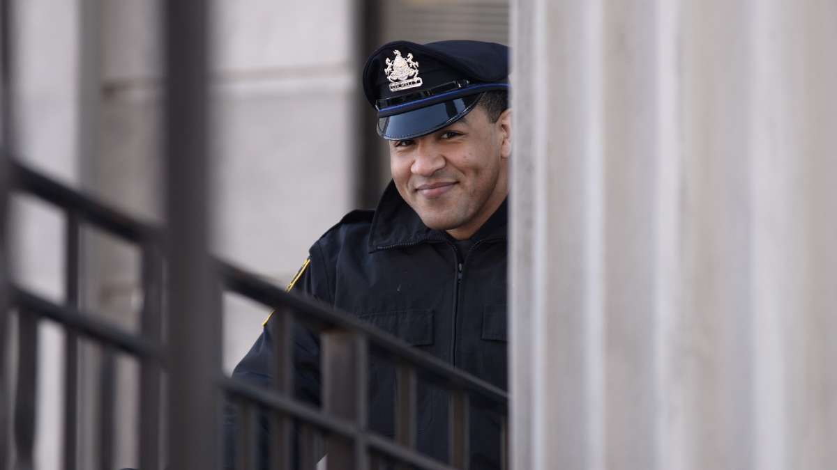 A police officer smiles from behind a column at the Montgomery County Courthouse.