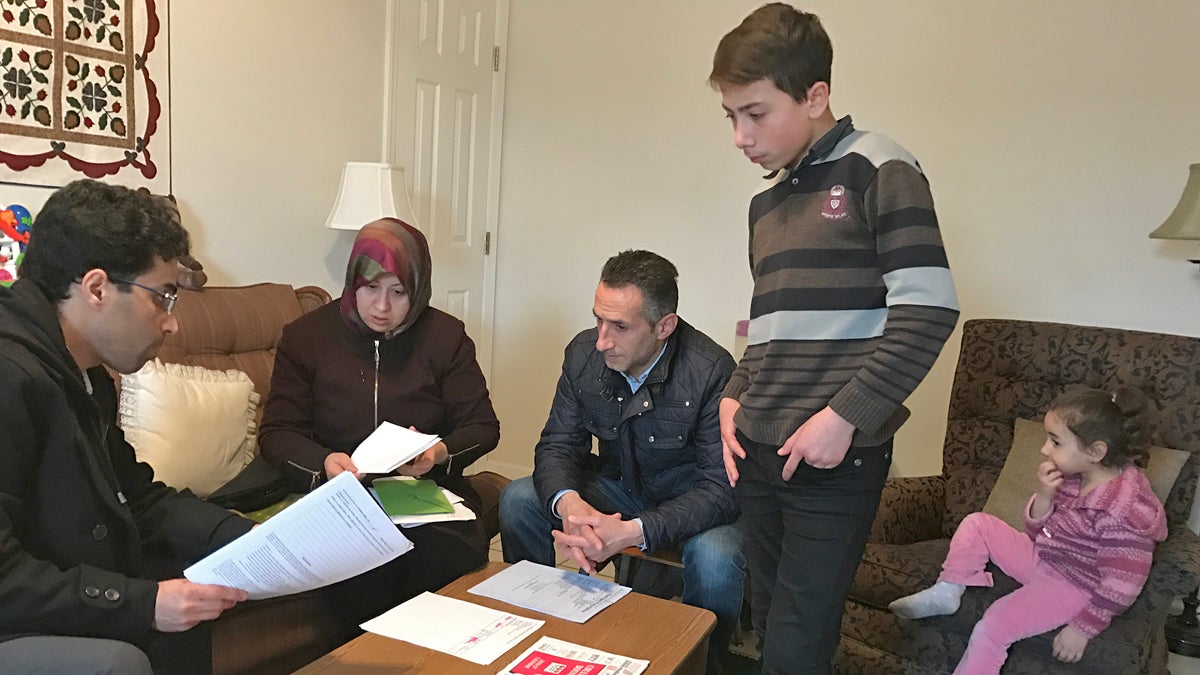  Amer Alfayadh, caseworker for Church World Service's Lancaster office, reviews paperwork with Marwa Hilani, her husband Imad Ghajar and children Mohamad, 14, and Lamar, 4. (Emily Previti/WITF) 