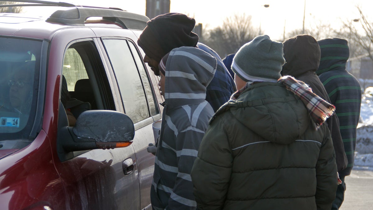 A dozen laborers crowd around a van in the Home Depot parking lot. One is chosen and the rest go back to their vigil. (Emma Lee/for NewsWorks) 