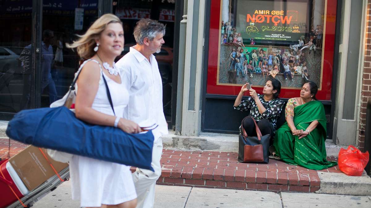 Bystanders on Arch Street watch the parade of white clad people on their way to Dîner en Blanc at Franklin Square Park. (Brad Larrison for NewsWorks)