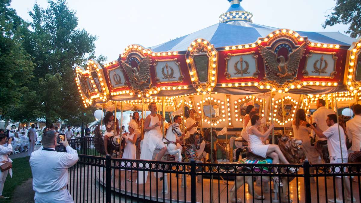 Diners ride the carousel in Franklin Square Thursday evening during the sixth annual Dîner en Blanc. (Brad Larrison for NewsWorks)