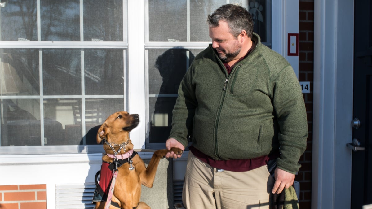  Russel Keyser shaking hands with his service dog, Artemis. (Paige Pfleger/WHYY) 