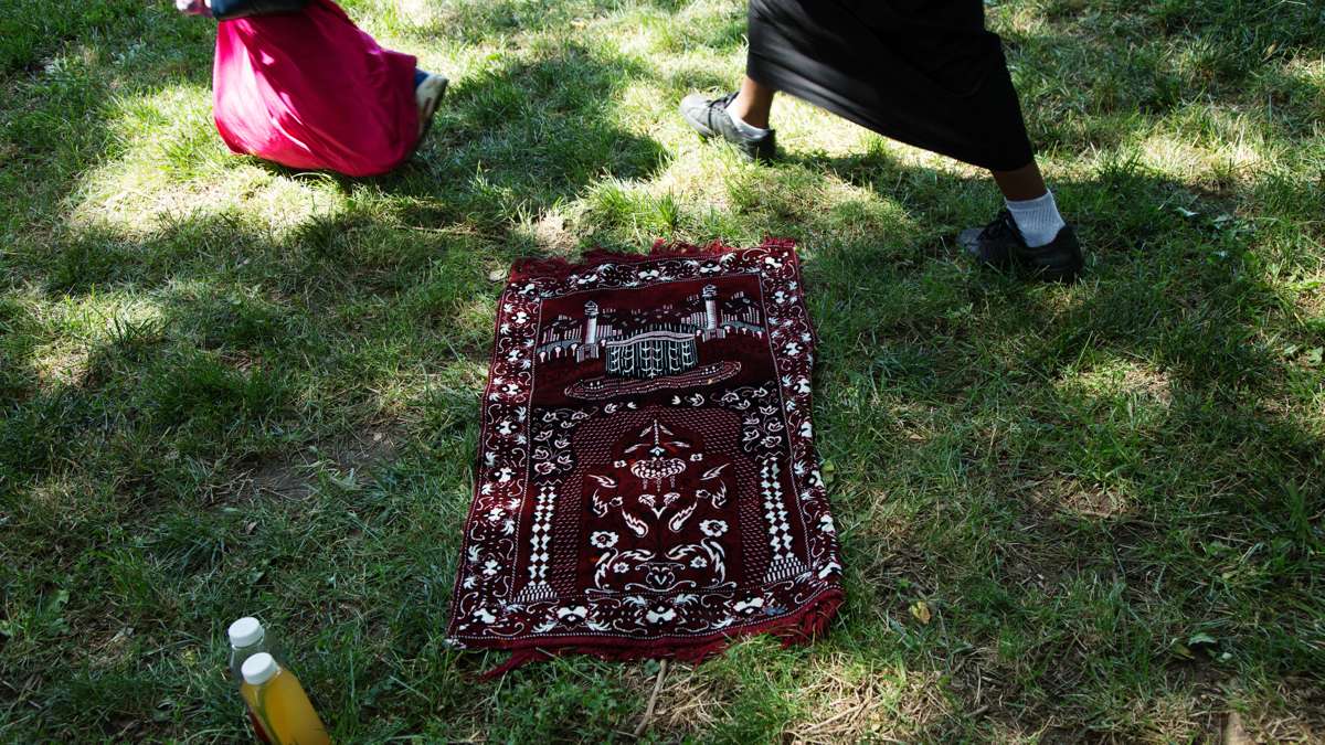 A prayer rug lies in the grass in Clara Muhammad Square