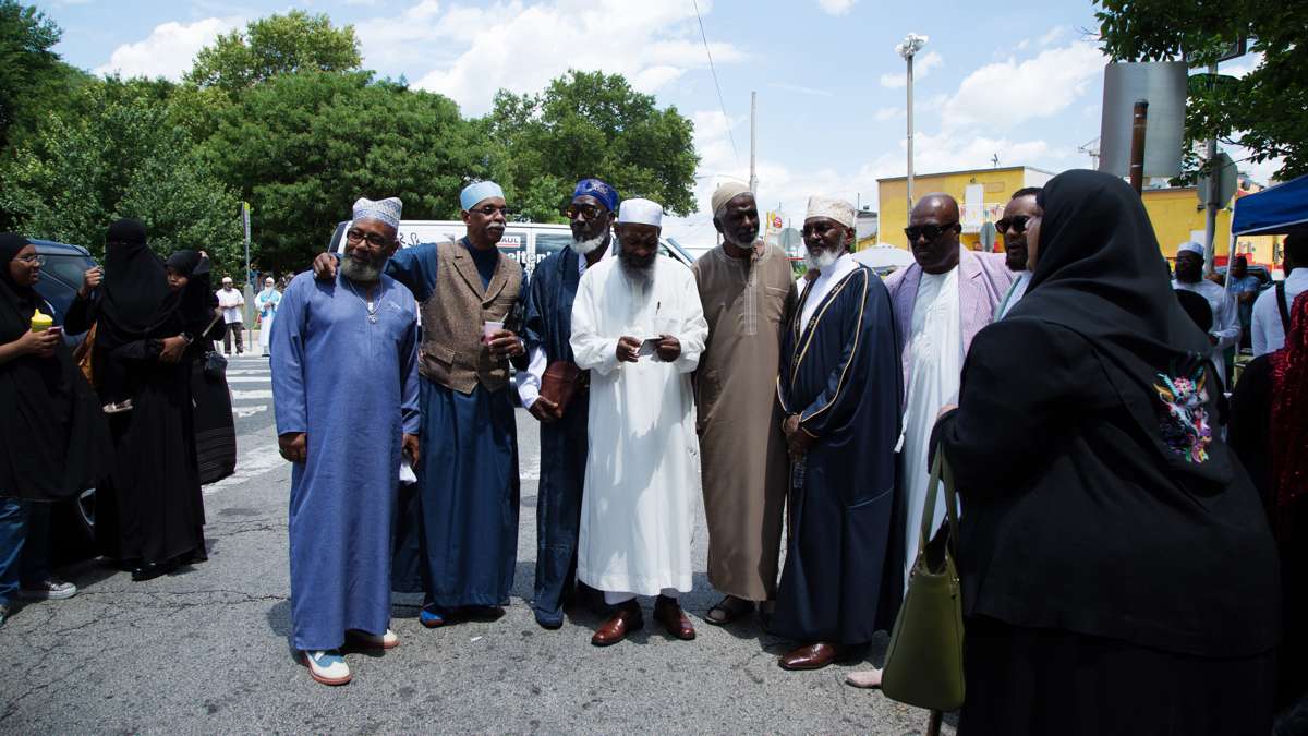 Men pose for a group portrait in front of Clara Muhammad Square