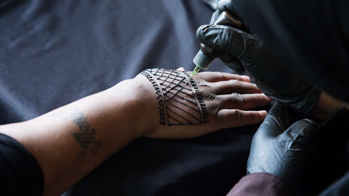A woman paints henna on to the hand of a client at FDR Park