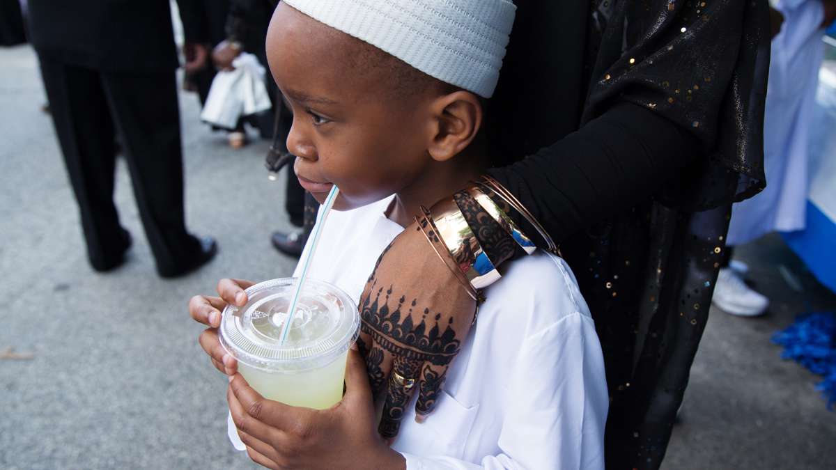 A boy stands with his mother on 47th Street outside of Philadelphia Masjid