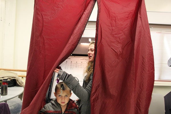 <p>First time voter Samantha DeCarlo draws back the curtain of a voting booth in Ventnor to ask her mother for help. (Emma Lee/for NewsWorks)</p>
