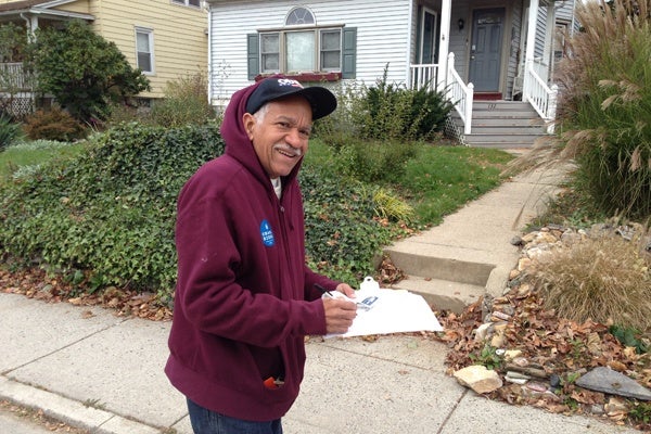 <p>Volunteer Samuel Brackeen was knocking on the doors in Glenside encouraging anyone at home to vote.  For those who were not in, he was leaving a reminder sticker.  (Jeanette Woods/WHYY)</p>
