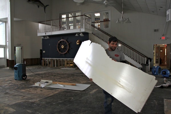 <p>Ed Colavita helps to clean out the Ocean City Yacht Club after it was innundated by Hurricane Sandy. Those who usually vote at the club were sent to a nearby church to cast their ballots. (Emma Lee/for NewsWorks)</p>
