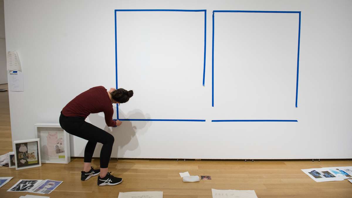 Sasha Diehl tapes the location of two of her large paintings on the gallery wall.