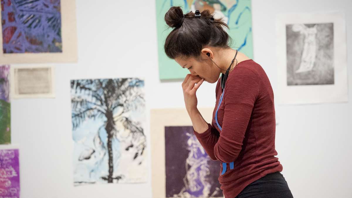 With her paintings laid out on the floor, Sasha Diehl contemplates hanging her work on the gallery wall.