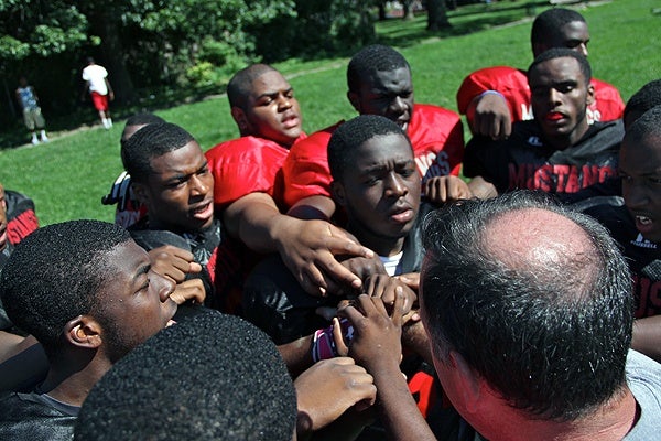 Football players huddle around Dobbins-Randolph Vo-Tech High School Coach John Sullivan.