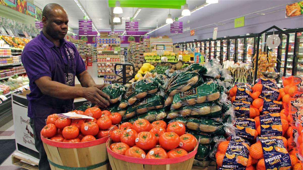 Produce manager Nate Sumpter arranges fresh fruits and vegetables at Fare and Square in Chester. (Emma Lee/WHYY)