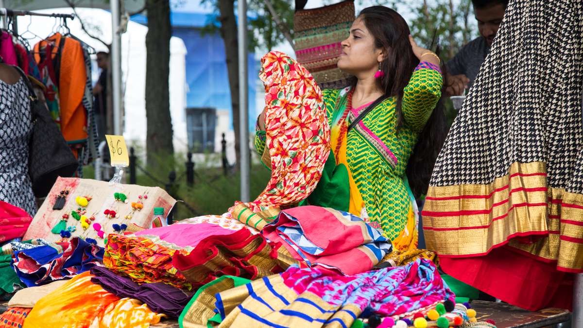 Nirali Dhada sorts her saris for sale during the Festival of India at Penn's Landing. (Emily Cohen for NewsWorks)