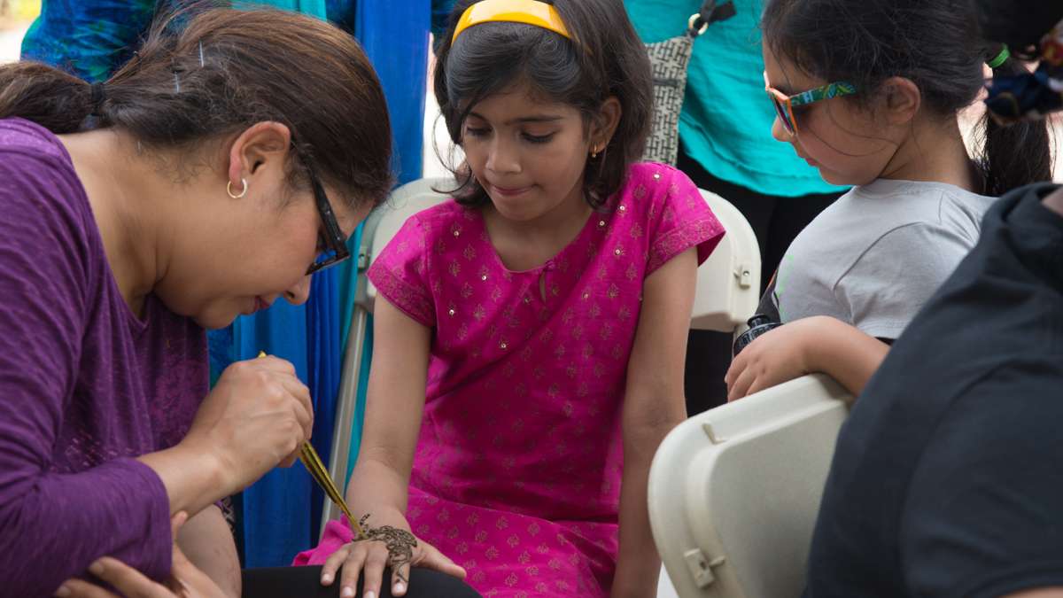 Amrit Singh (left), paints a henna design on Lavanya Dixit, 8, as her friend Kashish Pandey, 5, looks on. Singh works with 100 percent natural ingredients in her henna at her shop Natural Touch in Newark, Delaware. (Emily Cohen for NewsWorks)