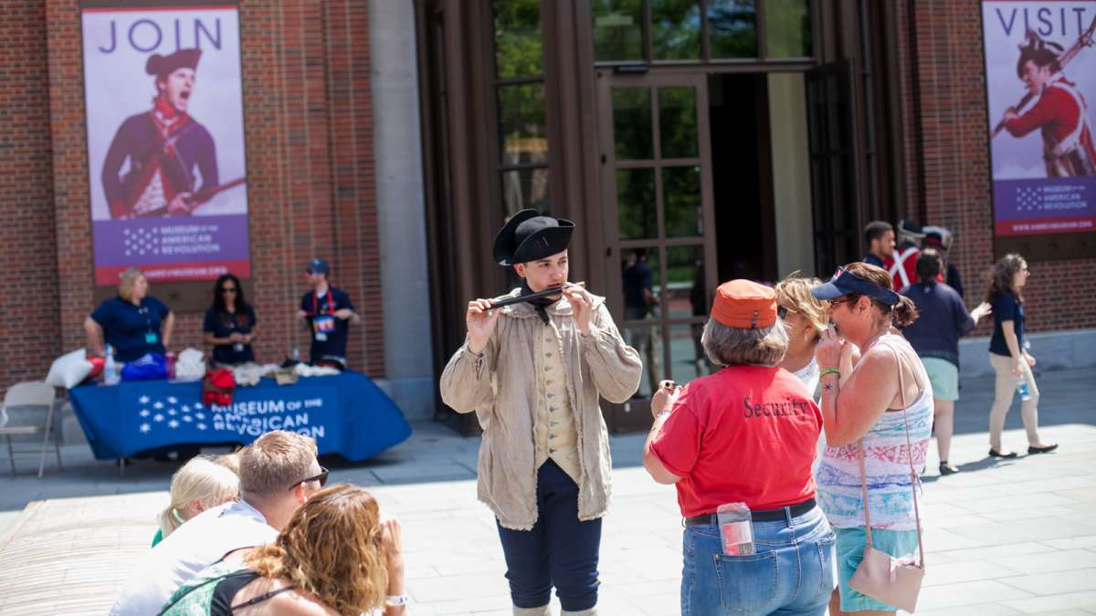 Matthew Skic, assistant curator of the event, demonstrates the fife to museum goers out outside of the Museum of the American Revolution Saturday. (Brad Larrison for NewsWorks)