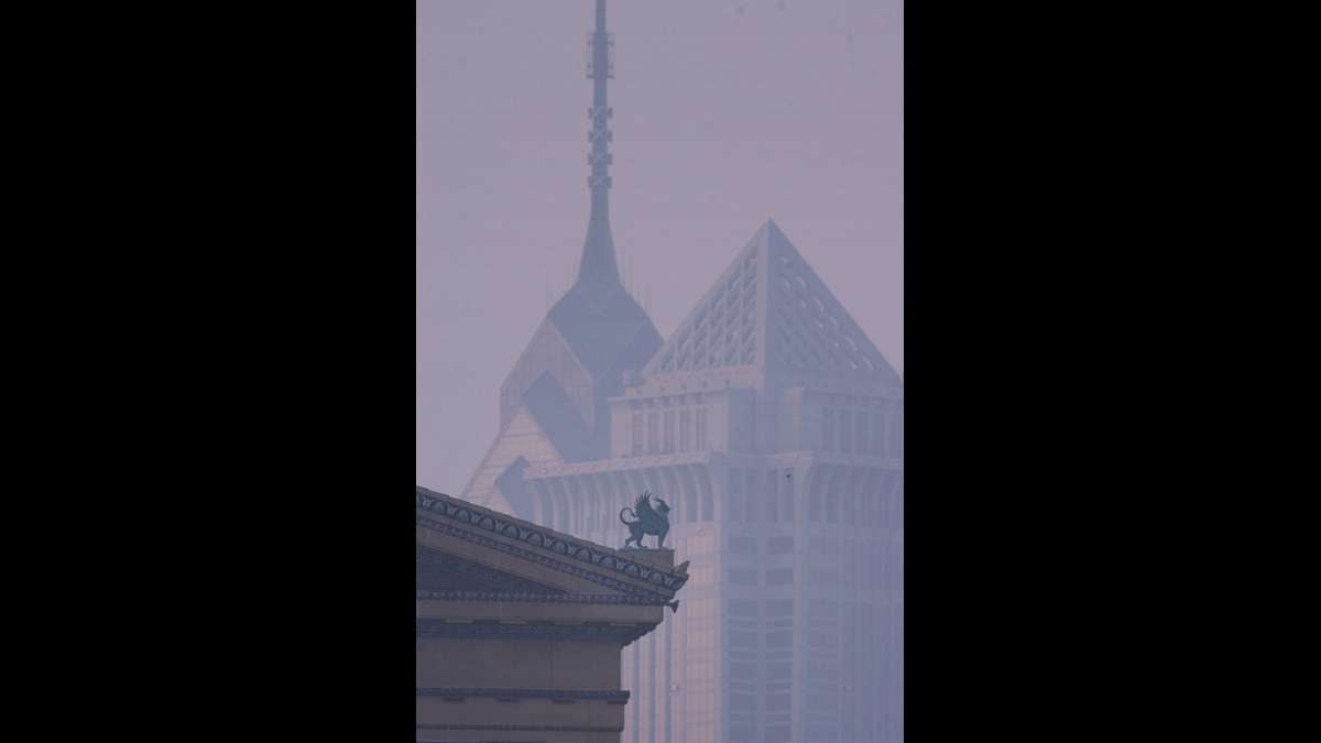 A griffon on the roof ot the Philadelphia Museum of Art is silhouetted by mist against the Philadelphia skyline at dawn.