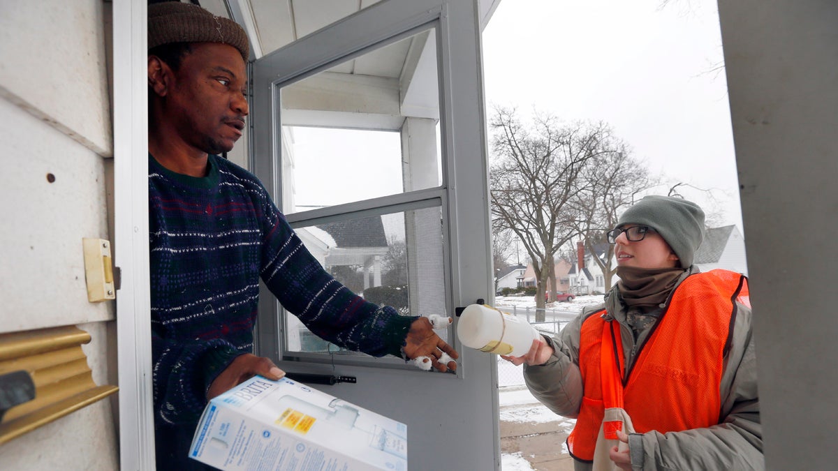  Louis Singleton receives water filters and a test kit from Michigan National Guard Specialist Jelena Tasevska Thursday, Jan. 21, 2016 in Flint, Mich. The National Guard, state employees, local authorities and volunteers have been distributing lead tests, filters and bottled water during the city's water crisis. (AP Photo/Paul Sancya) 