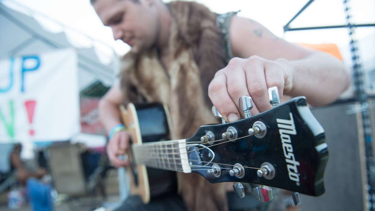 Evan Abrams of Runnemede, New Jersey, tunes his guitar in the campgrounds at the Philadelphia Folk Festival in Schwenksville, Pennsylvania. (Jonathan Wilson for NewsWorks)