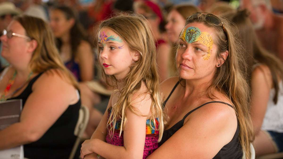 Cindy Irvin and her daughter Vera Meredith listen to Susan Werner perform in the Culture Tent. Irvin has attended 20 festivals while her daughter has attended four. (Jonathan Wilson for NewsWorks)