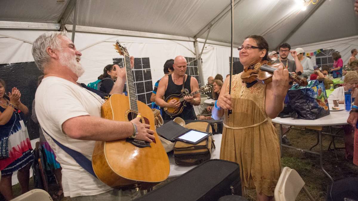 Guitarist Jerry Krantman and violinist Diane Perry jam during a brief rain shower on Saturday evening. (Jonathan Wilson for Newsworks)