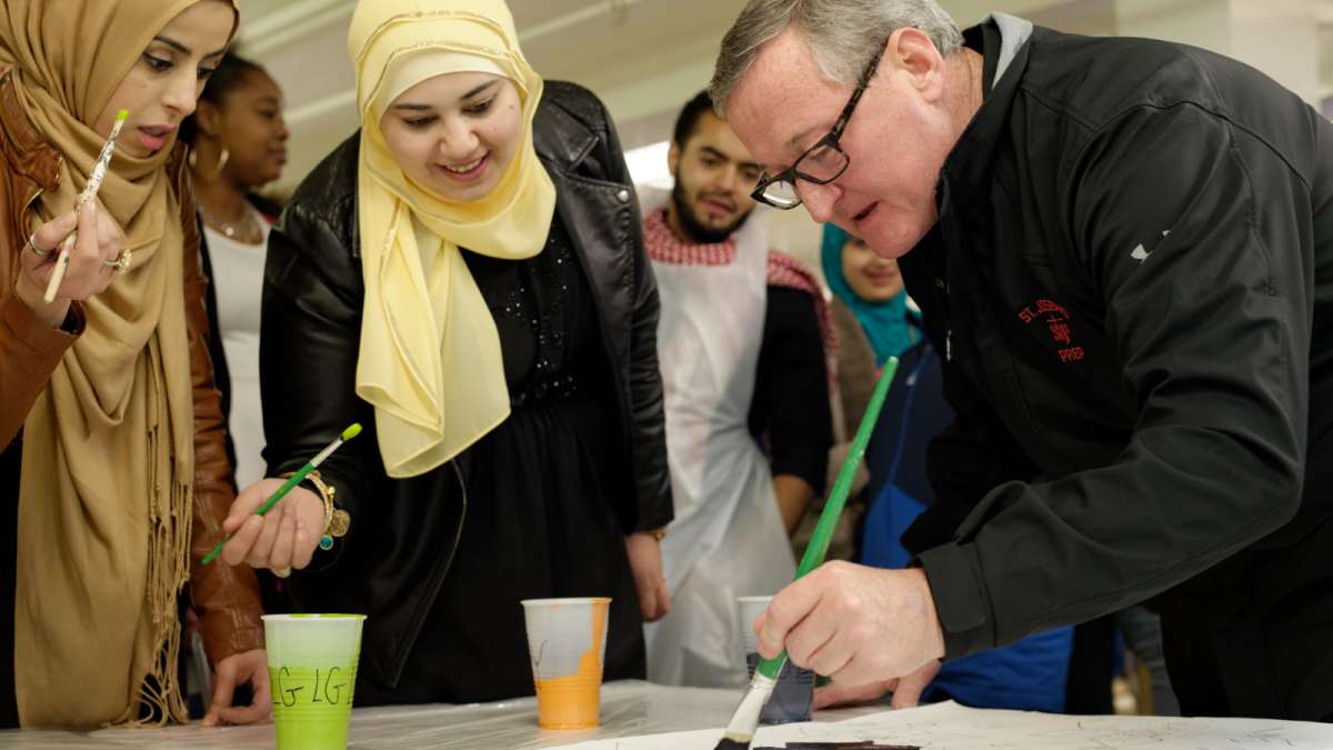 Safaa Deeb, Al-Aqsa youth club member, and Amneh Ahmad, Arab-American Community Development Corporation associate director, watch as Mayor Jim Kenney helps with the painting. (Bastiaan Slabbers/for NewsWorks)  