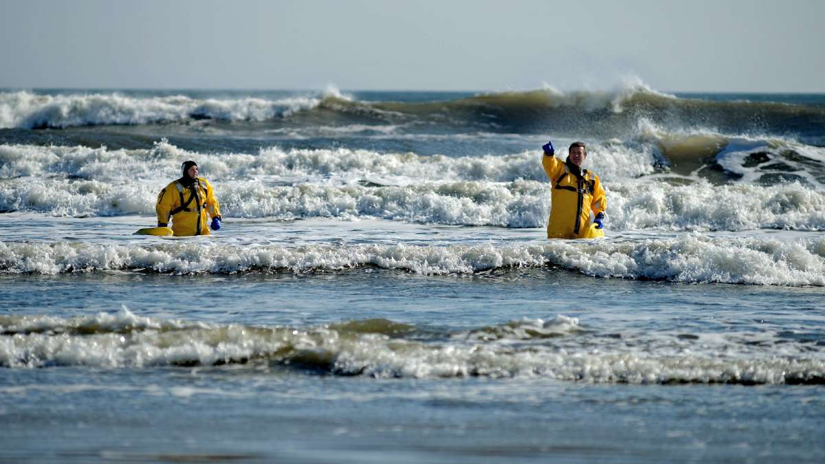 Divers of Wildwood and Middle Township Police Departments stand waist deep in the surf as they wait for the plungers to hop in. (Bastiaan Slabbers/for NewsWorks)
